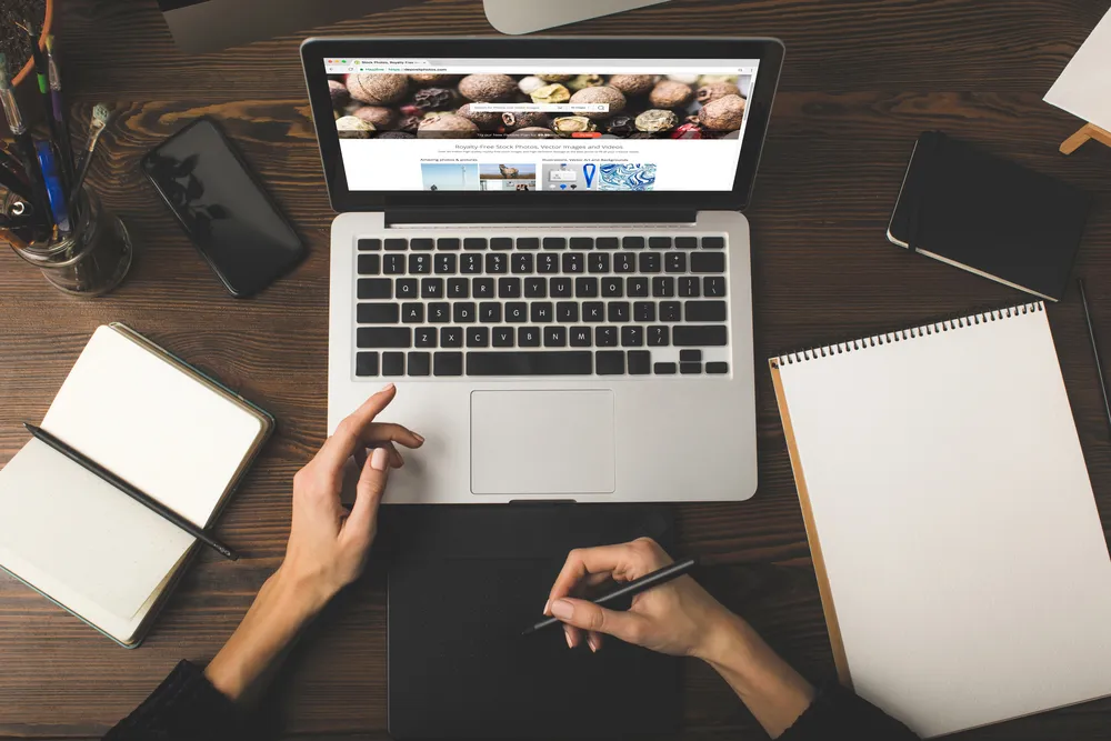 Dizajnerica izrađuje web stranicu na grafičkom tabletu uz laptop