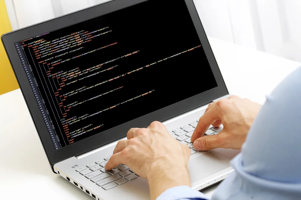 Ruke na tipkovnici laptopa tijekom pisanja koda web stranice