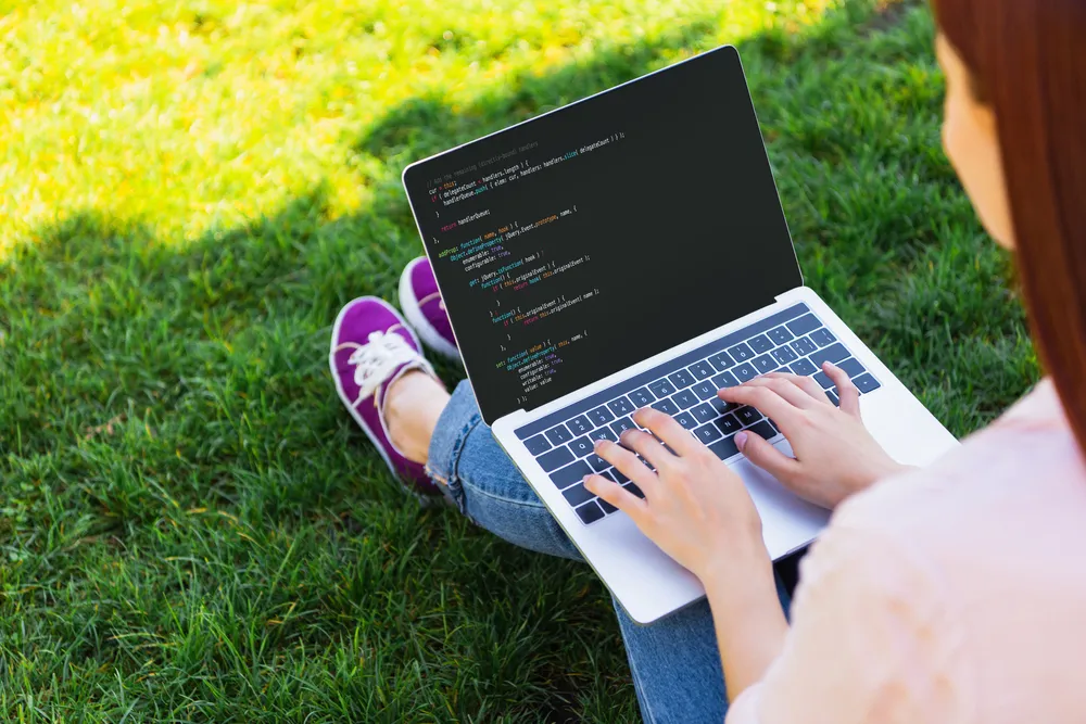 Osoba programira web stranicu na laptopu na otvorenom