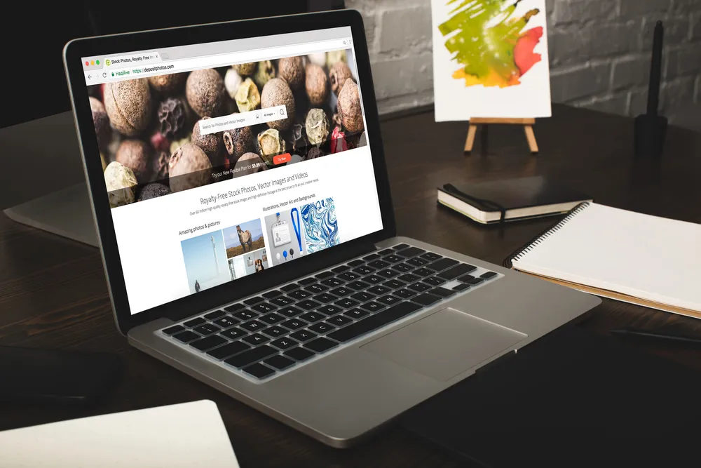 Laptop s otvorenom web stranicom na tamnom radnom stolu
