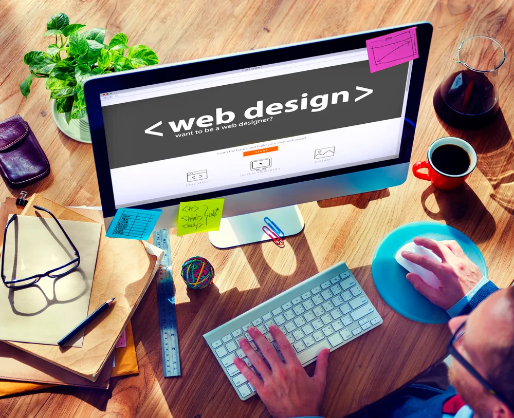Monitor s natpisom web design na kreativnom radnom stolu